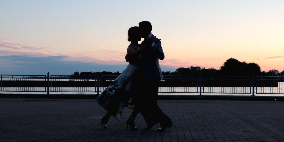 Couple dancing in front of sunset on pier